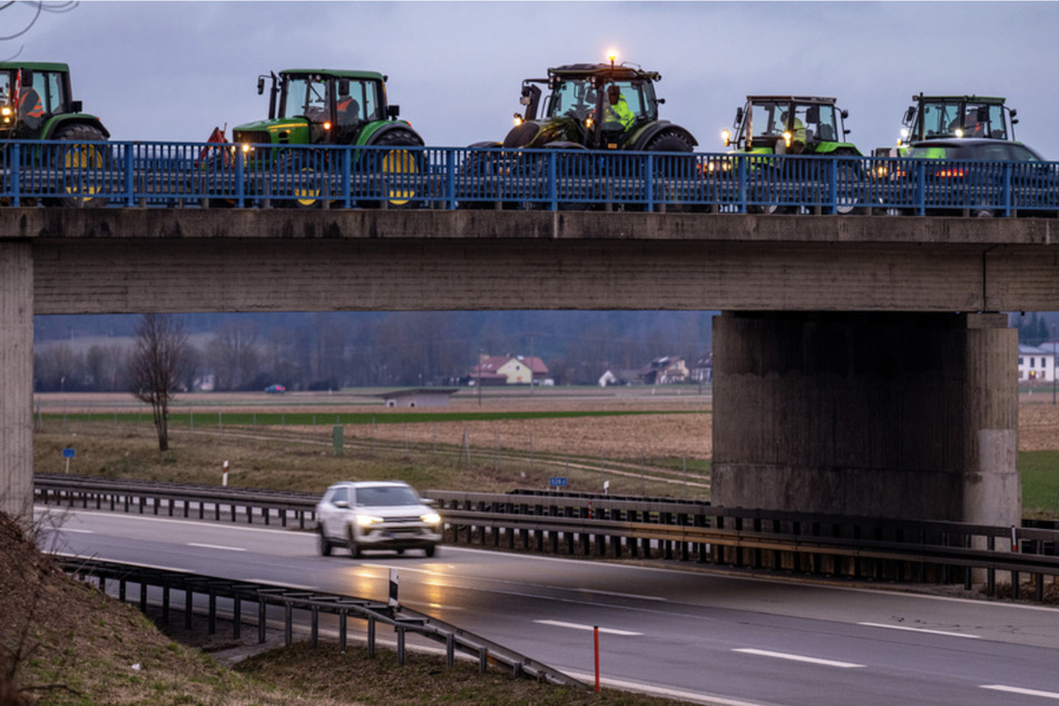 Traktoren von protestierenden Landwirten stehen auf einer Brücke über der Autobahn A3 bei Kirchroth.