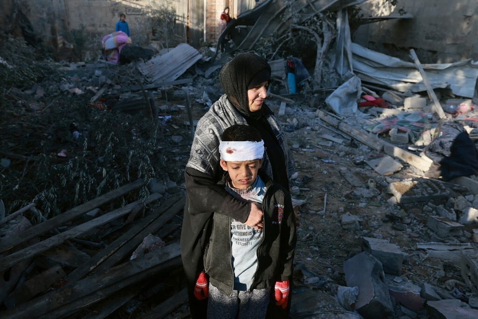 A Palestinian woman embraces an injured boy as they check the rubble of a building following Israeli bombardment on January 18, 2024, in Rafah in the southern Gaza Strip.