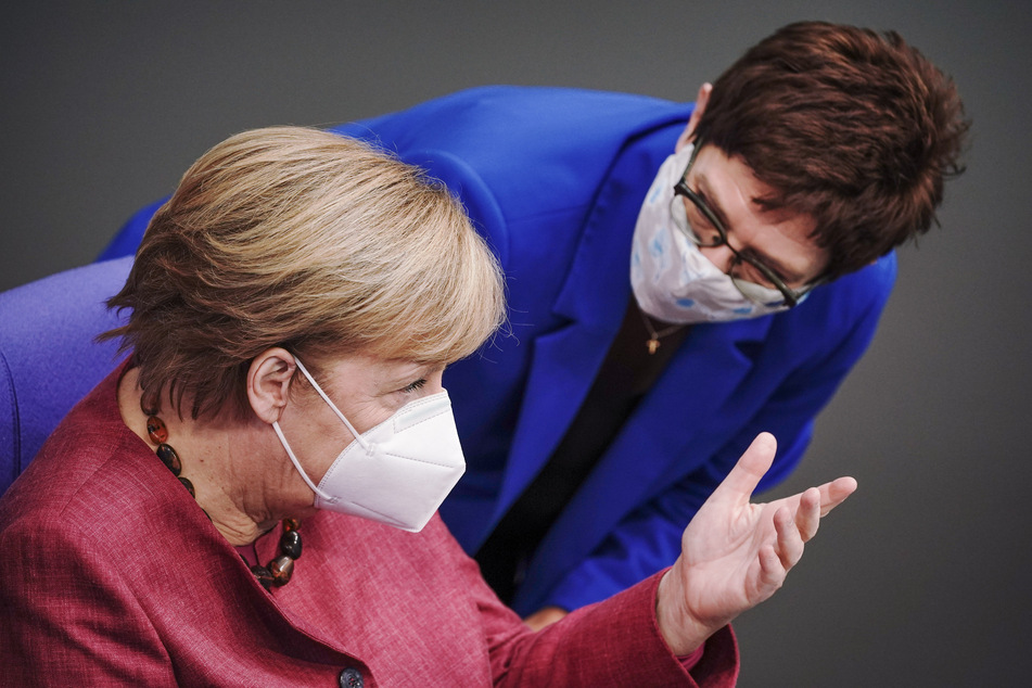 Bundeskanzlerin Angela Merkel (l) und Annegret Kramp-Karrenbauer (beide CDU), Bundesministerin der Verteidigung und CDU-Bundesvorsitzende, unterhalten sich mit Mund-Nasenbedeckung in der Sitzung des Bundestags. Kramp-Karrenbauer widerspricht der Kritik ihres Parteikollegen Friedrich Merz.