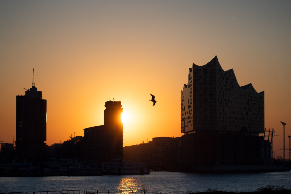 Die Sonne geht über der Hafencity hinter der Elbphilharmonie auf.