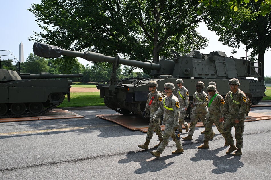 Soldiers walk past a M109 Paladin self-propelled howitzer taking part in the Army's 250th birthday celebration parade during a preview at West Potomac Park in Washington DC on June 11, 2025.