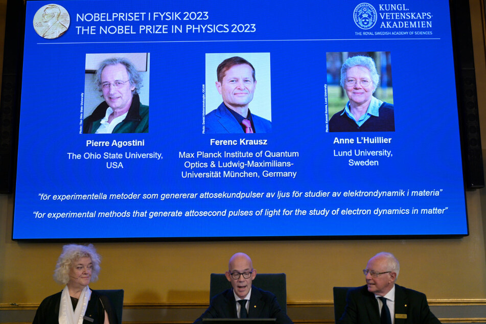 Neben zwei Kollegen aus den USA und Schweden wird der Direktor am Max-Planck-Institut für Quantenoptik, Ferenc Krausz (auf der Leinwand mittig), mit dem Physik-Nobelpreis ausgezeichnet.