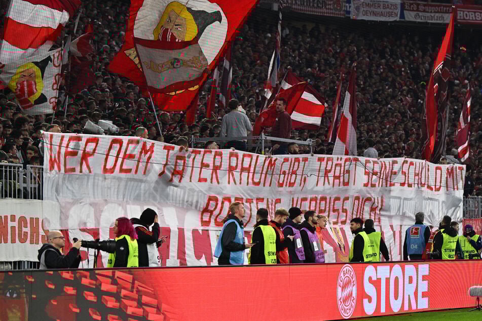 "Wer dem Täter Raum gibt, trägt seine Schuld mit", steht auf einem Banner der Bayern-Fans.