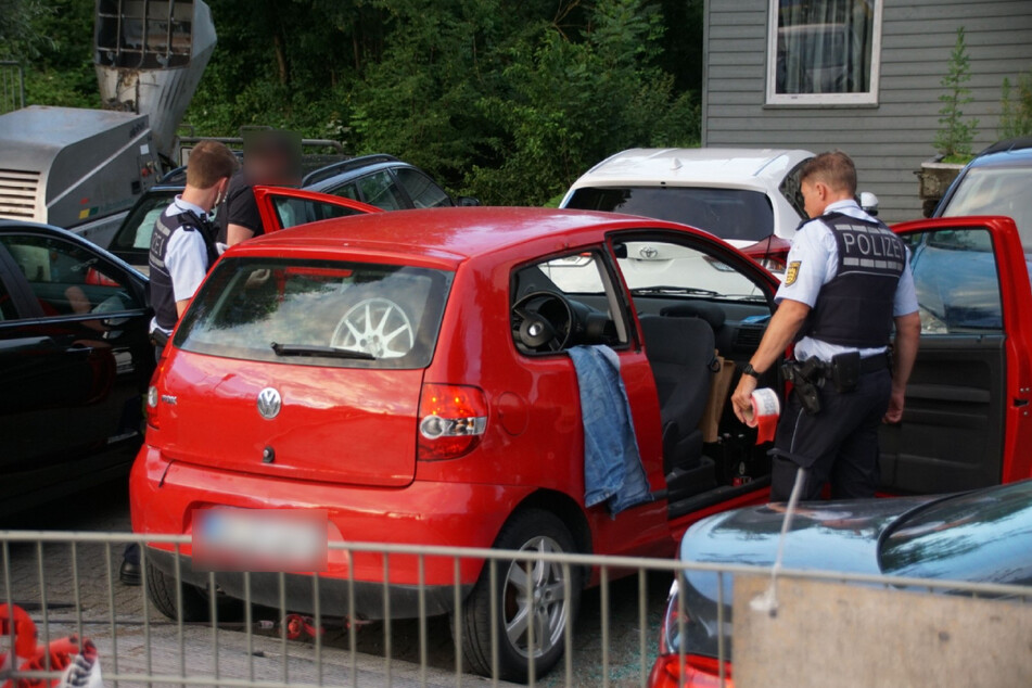 Polizisten untersuchen einen roten VW.