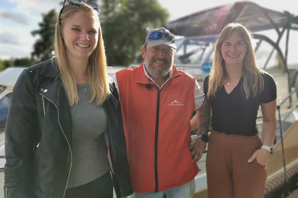 Natalie Maag (v.l.), Heino Brandt und Julia Taubitz vor der Yacht im Hafen von Eldenburg.