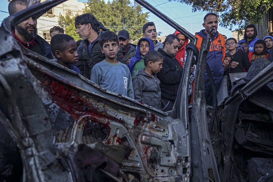 Onlookers gather around a car that was destroyed in an Israeli raid in Rafah in the southern Gaza Strip on Tuesday, amid ongoing battles between Israel and the armed Hamas movement.