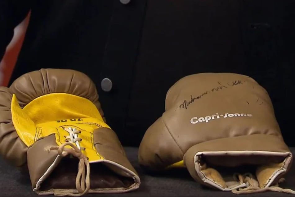 Boxhandschuhe mit der Original-Unterschrift von Muhammad Ali liegen auf dem Experten-Pult.