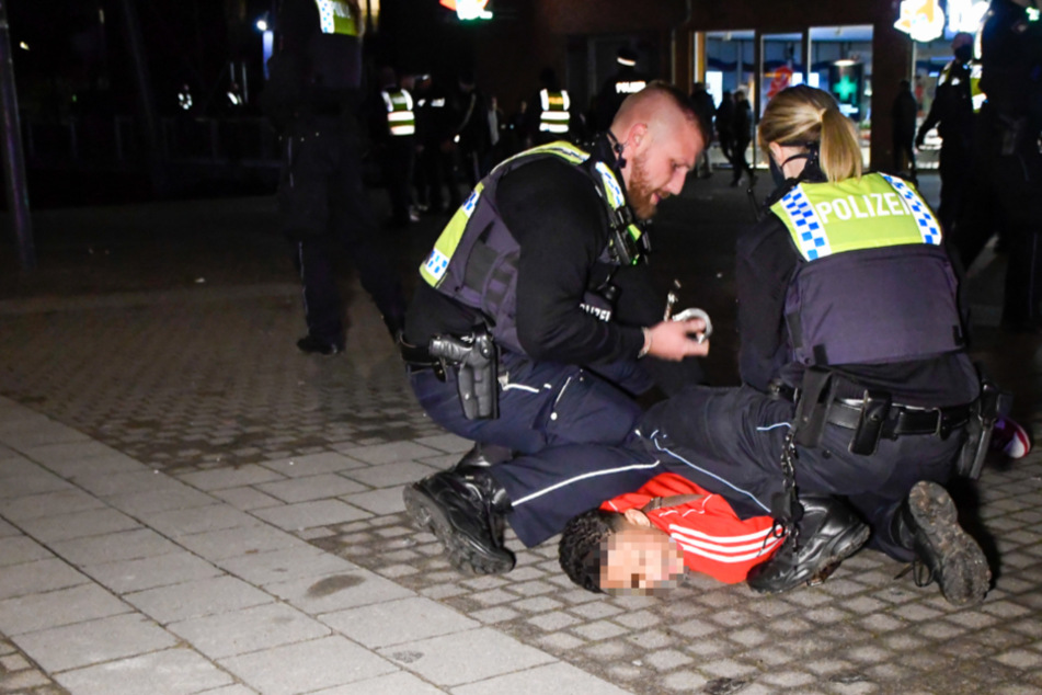 Polizisten nehmen einen jugendlichen Randalierer in Gewahrsam.