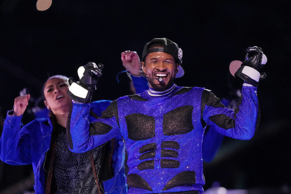 Usher dons a sparkly blue and black outfit as he performs during Super Bowl LVIII.
