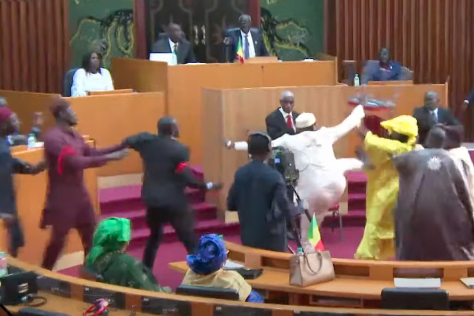 Ein Abgeordneter setzt zum High Kick an und trifft die aufgebrachte Parlamentarierin.