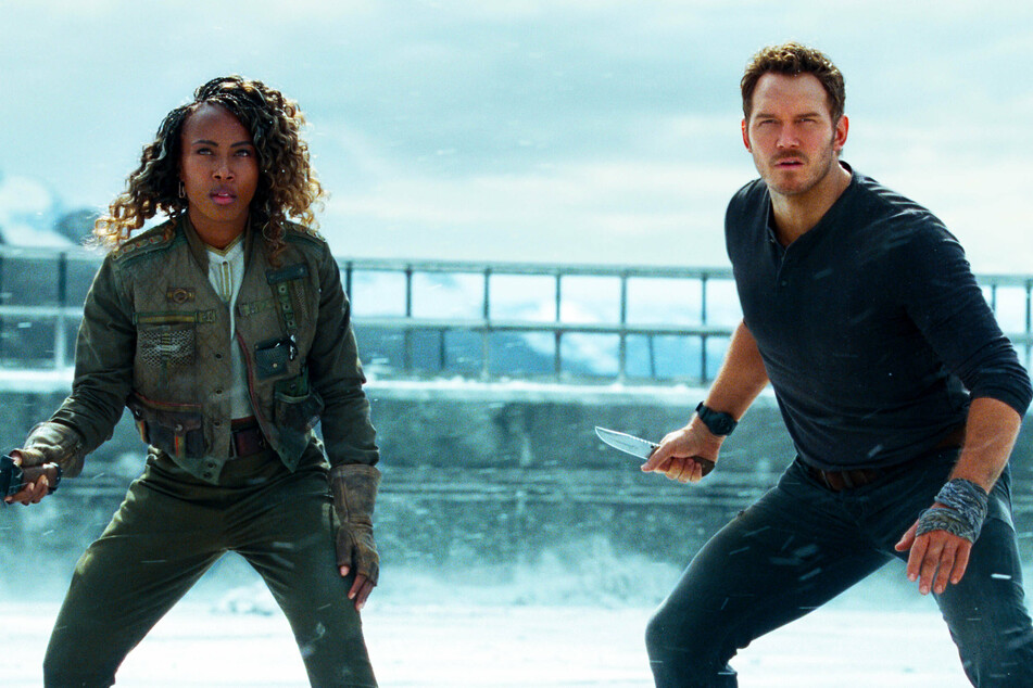 Chris Pratt (r) reprises his role as Owen Grady and DeWanda Wise plays Kayla Watts, a pilot who helps Owen, in Jurassic World Dominion.