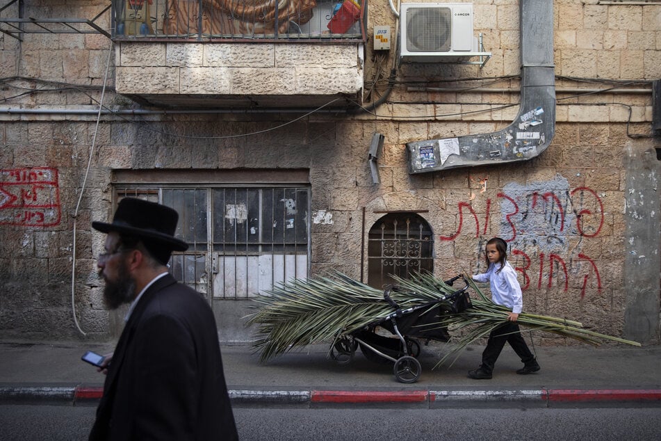 Jerusalem: Ein ultra-orthodoxes jüdisches Kind transportiert Palmwedel zum Bau einer Laubhütte anlässlich des bevorstehenden jüdischen Feiertags Sukkot.