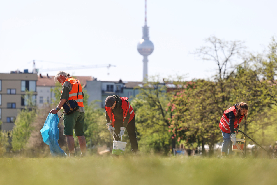 Freiwillige befreien den Mauerpark bei strahlendem Sonnenschein vom Müll.