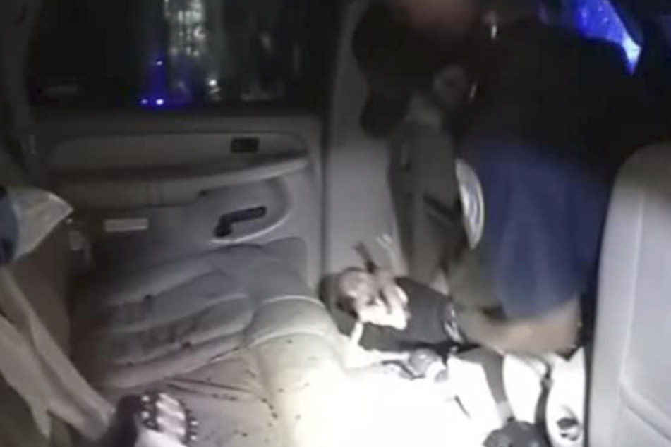 Bilder der Polizeikamera zeigen wie der Polizist das Neugeborene aus dem verunglückten Auto befreit.