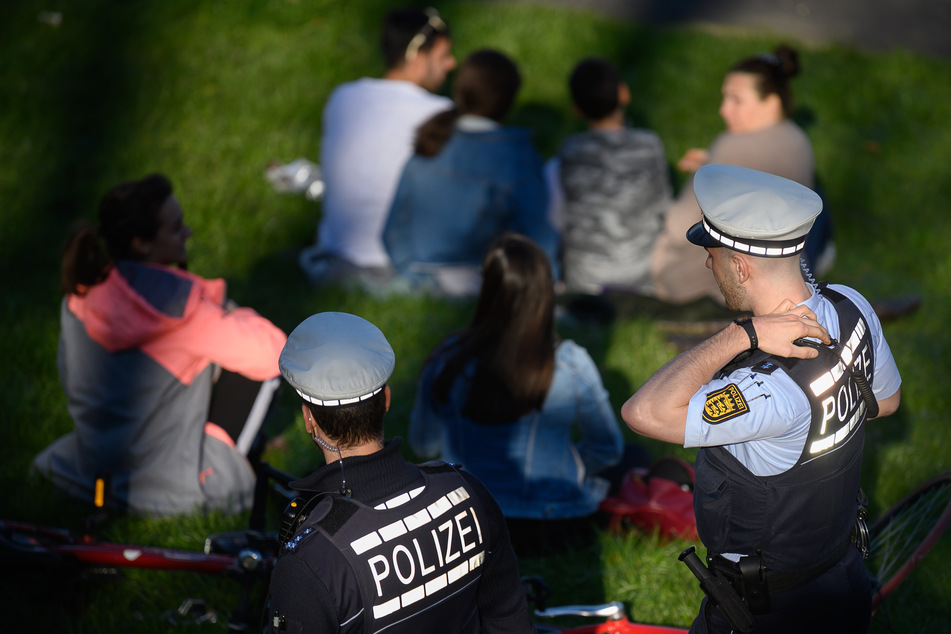 Polizeibeamte kontrollieren in einem Park die Einhaltung der Vorschriften zur Eindämmung des Coronavirus.