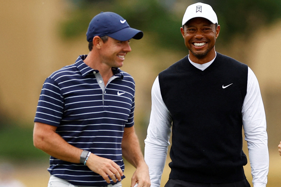 Golf stars Rory McIlroy of Northern Ireland and Tiger Woods of the US smile together during the Celebration of Champions four-hole tournament in St. Andrews, Scotland.