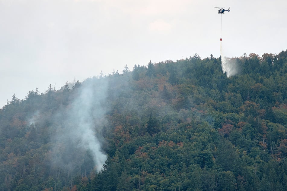 Ein Hubschrauber fliegt Löschwasser auf den Johannisberg. Die Feuerwehr kann nur zu Fuß in das Gelände vordringen.