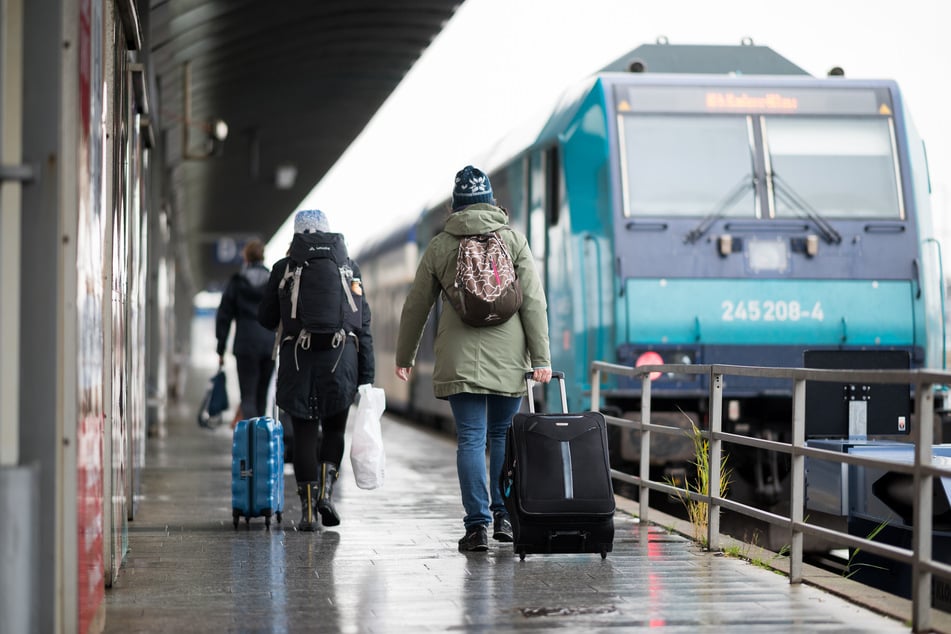 Reisende gehen im Bahnhof Westerland über einen Bahnsteig.