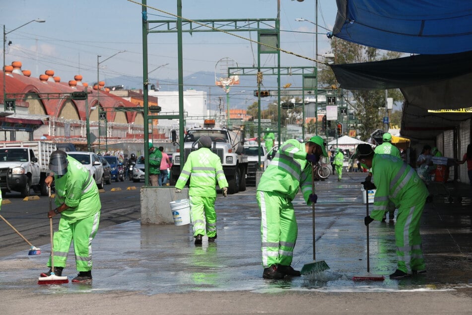 In Mexiko-Stadt reinigen Mitarbeiter der Straßenreinigung den Bürgersteig, um dem Coronavirus Einhalt zu gebieten.