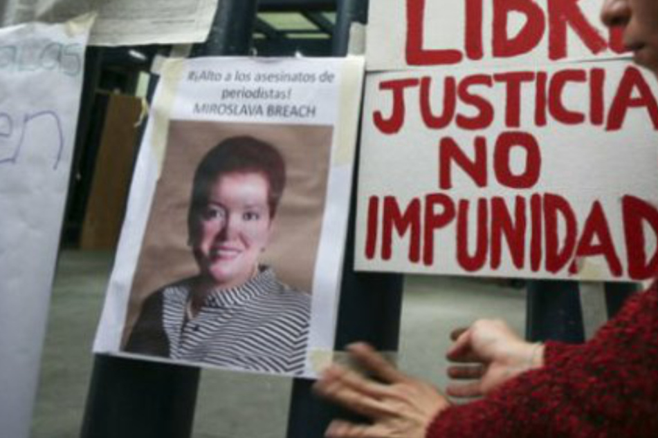 Eine Frau hängt ein Plakat auf, auf welchem die ermordete Journalistin Miroslava Breach zu sehen ist.
