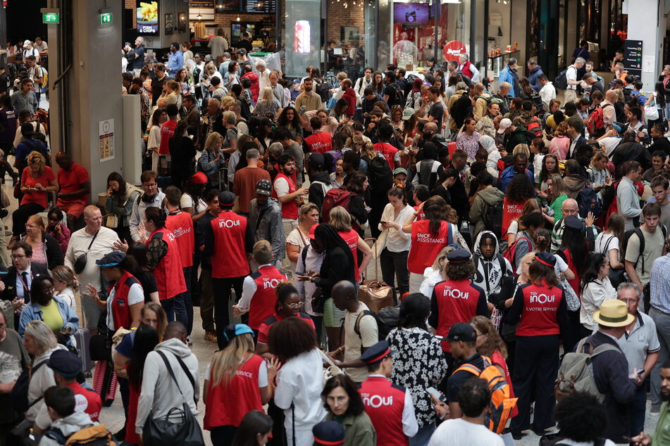 Employees of SNCF railway company speak to passengers waiting for their trains' departure at the Gare Montparnasse train station in Paris on Friday as France's high-speed rail network was hit by an attack disrupting the transport system just hours before the opening ceremony of the Paris 2024 Olympic Games.