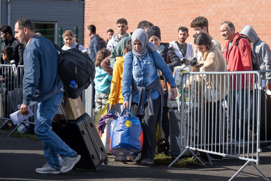 Flüchtlinge gehen in der hessischen Erstaufnahmeeinrichtung in Gießen zu einem wartenden Bus. Hier sind derzeit rund 3500 Menschen aus unterschiedlichen Ländern untergebracht.