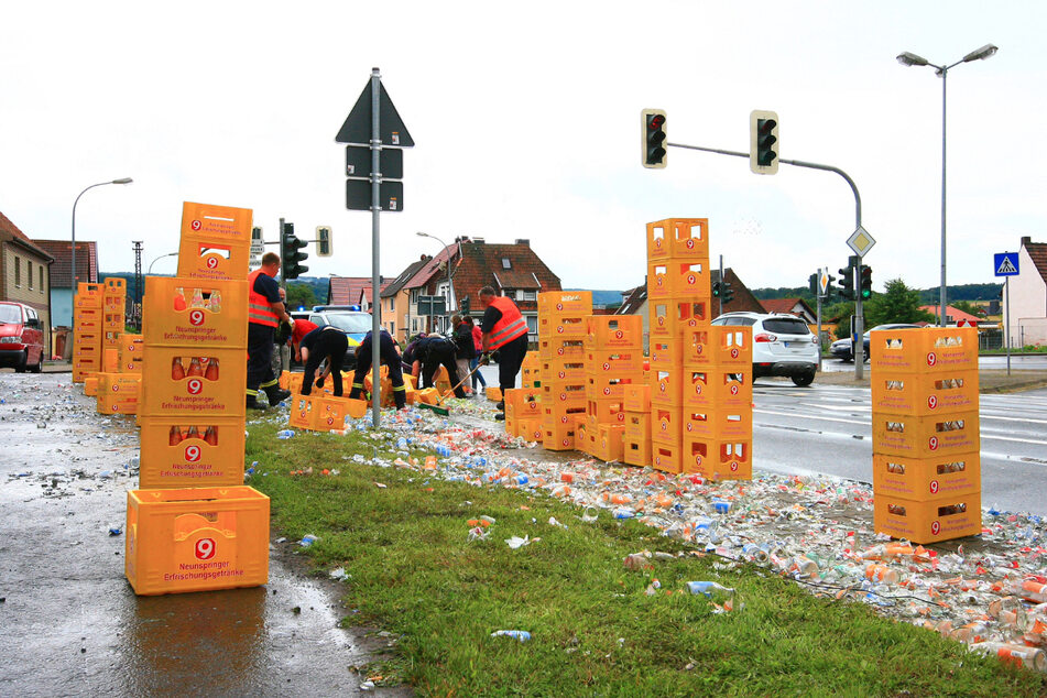 Die Einsatzkräfte kehren die Flaschen und Splitter zusammen.