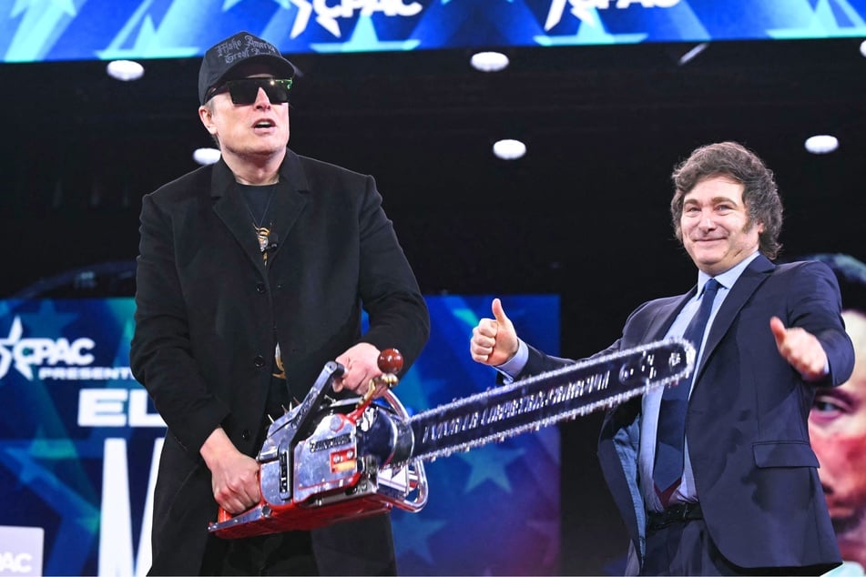 Elon Musk (L) holds a chainsaw gifted to him by Argentine President Javier Milei during the annual Conservative Political Action Conference (CPAC) in Oxon Hill, Maryland, on February 20, 2025.