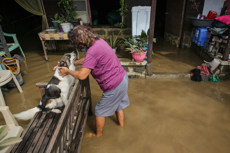 Eine Frau streichelt ihren Hund in ihrem überfluteten Haus, einen Tag nachdem der Tropensturm Nalgae schwere Regenfälle und starke Winde über die Philippinen gebracht hat.