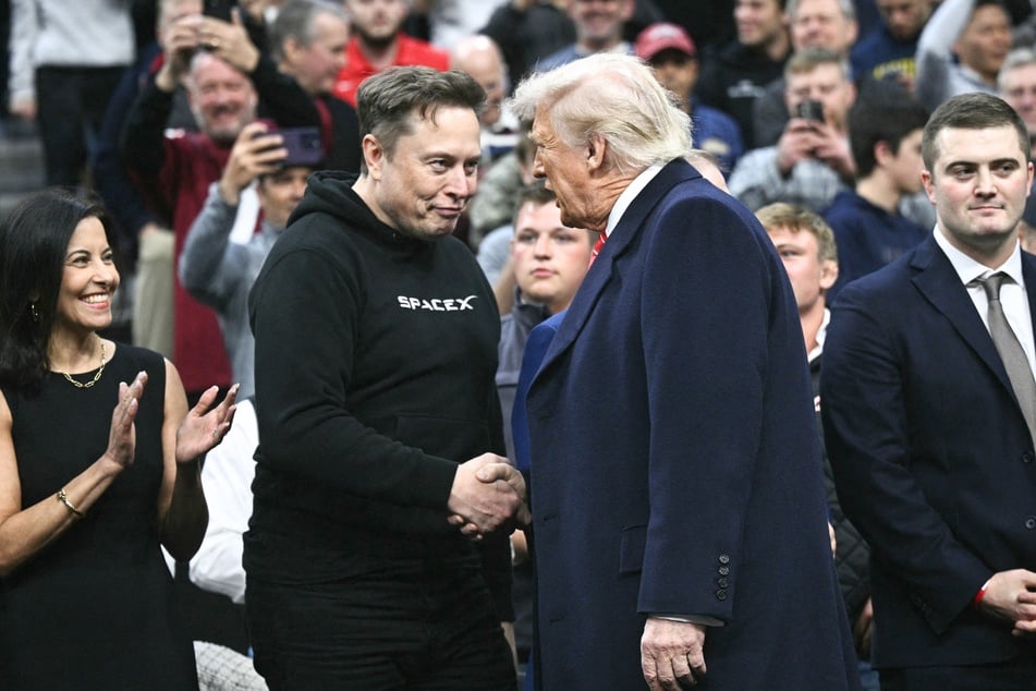Elon Musk (center l.) and President Donald Trump (center r.) shake hands as they attend the men's NCAA wrestling competition in Philadelphia, Pennsylvania, on March 22, 2025.