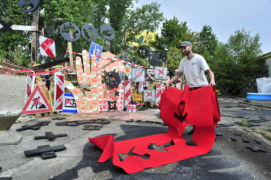 Christoph Mügge (36) bereitet sein Kunstwerk aus Schildern, Absperrungen und Piktogrammen vor.