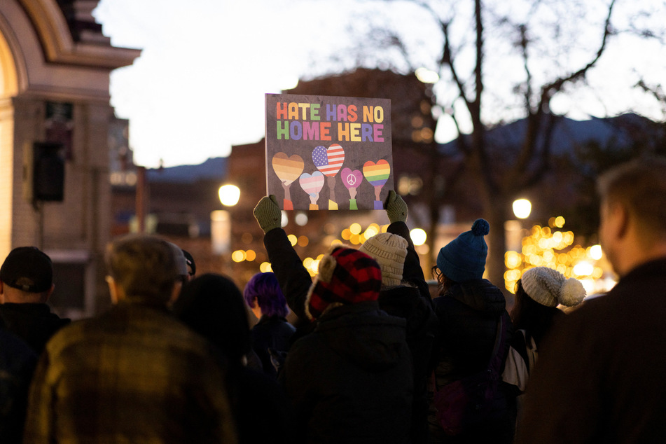 A person holds a sign during a vigil at Acacia Park for the victims of the mass shooting at Club Q in Colorado Springs.