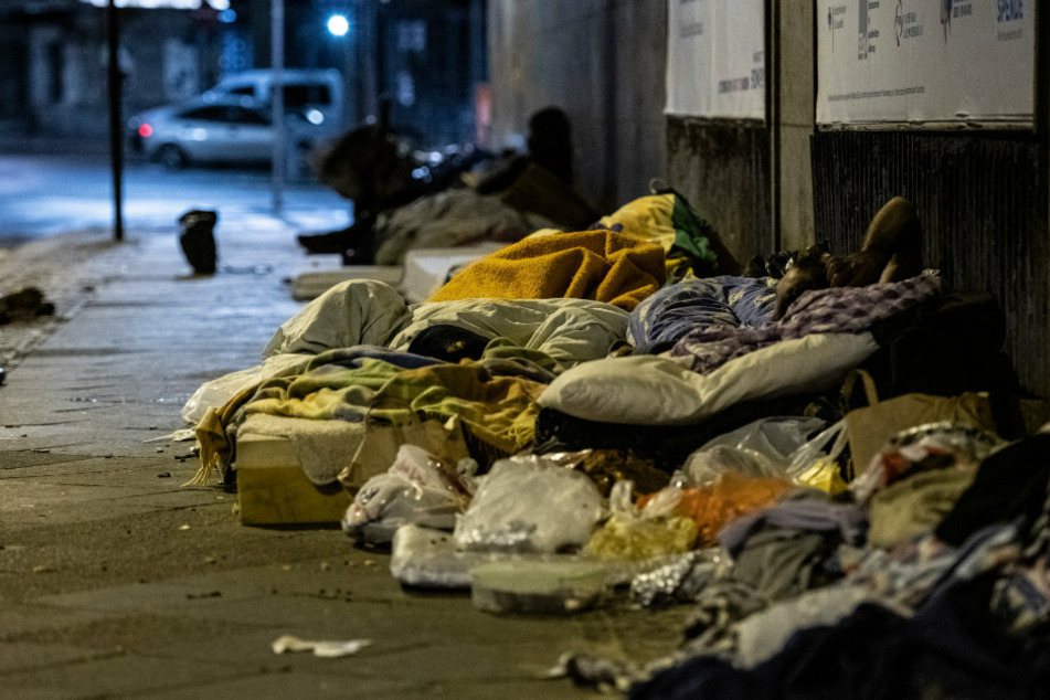 Obdachlose Menschen liegen unter einer Brücke am Zoo.