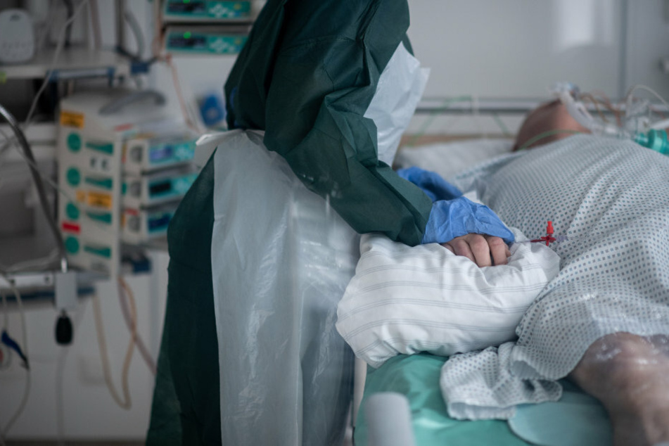 Eine Mitarbeiterin der Pflege in Schutzausrüstung betreut einen Corona-Patienten. Die Brandenburger Kliniken leiden nach Angaben der Landeskrankenhausgesellschaft in der Corona-Krise unter Personalausfällen.
