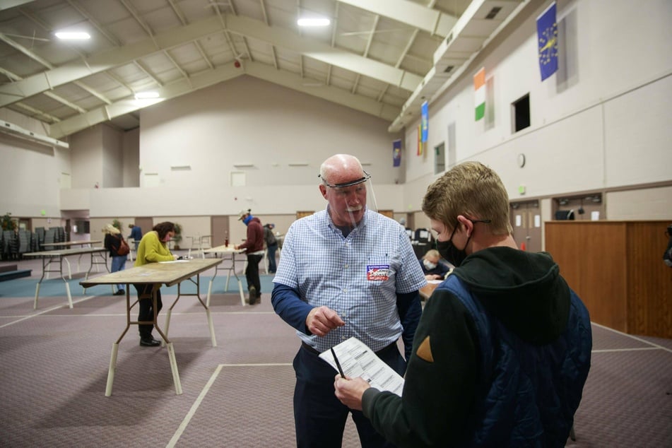 A poll worker helps a voter with information about how to cast a ballot at the Southside Christian Church in Bloomington, Indiana.