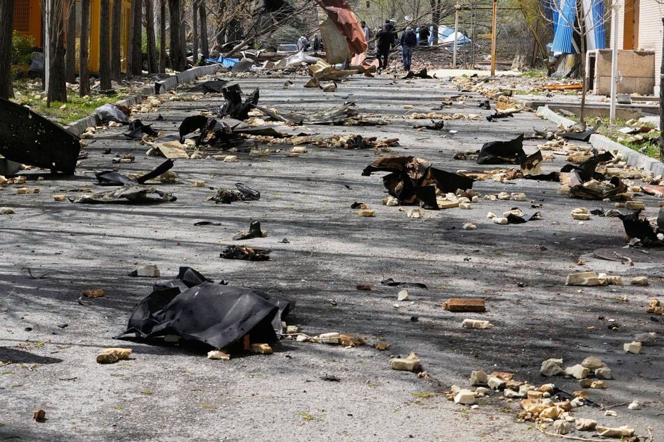 Trümmer liegen auf einer Straße neben dem Ort der Luftangriffe.