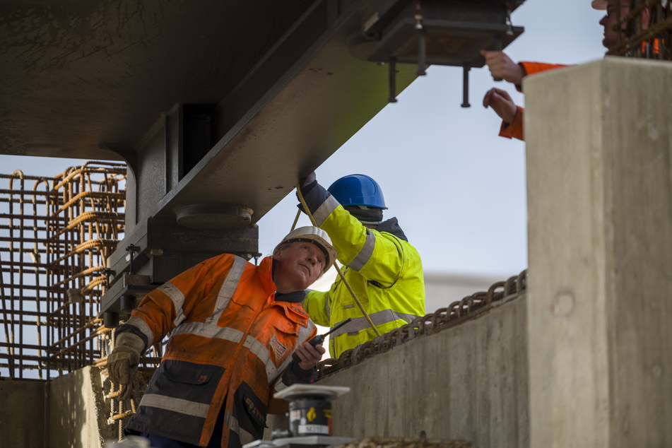 Strabag-Mitarbeiter setzen einen 100 Tonnen schweren Stahlträger passgenau auf Beton-Widerlager.