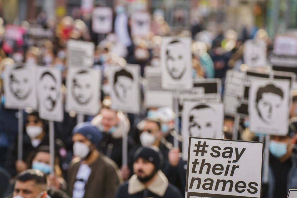 Ein Plakat "#say their names" wird auf der Kundgebung am 19. Februars zum Gedenken an den rassistischen Anschlag vor einem Jahr in Hanau hochgehalten.