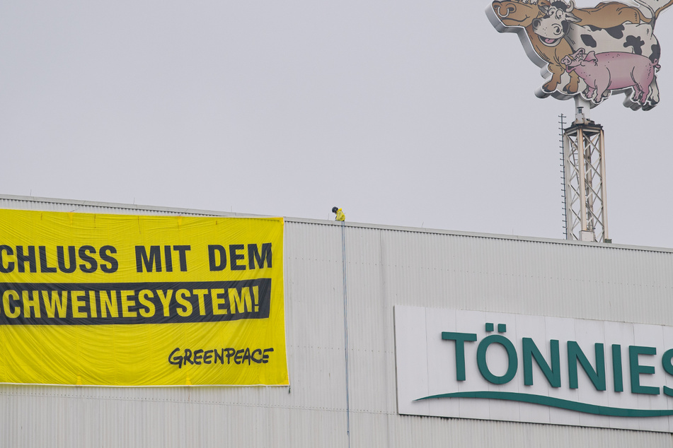 Zwei Greenpeace-Aktivisten landeten mit ihren Gleitschirmen auf dem Dach des Fleischwerkes des Branchenführers Tönnies in Rheda-Wiedenbrück und rollen ein Transparent mit der Aufschrift "Schluss mit dem Schweinesystem!" aus.