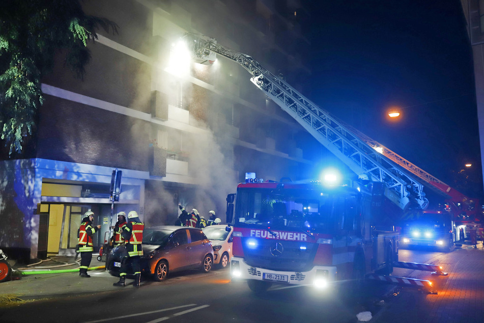 Feuerwehrleute löschen den Brand in dem mehrstöckigen Haus und evakuieren über die Drehleiter Bewohner aus höher gelegenen Wohnungen.