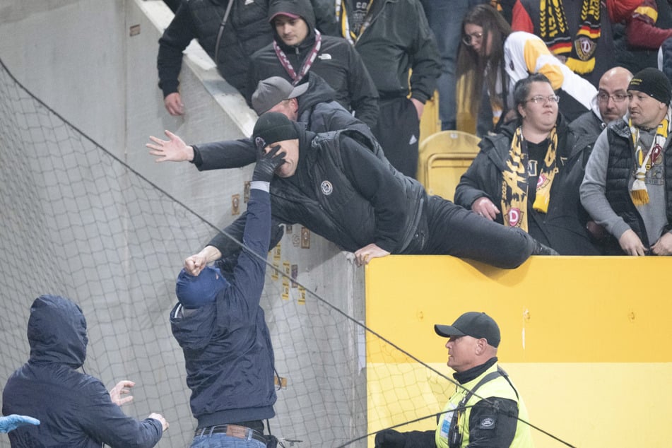 Ein vermummter Hertha-Fan nimmt es mit einem Dynamo-Anhänger auf.