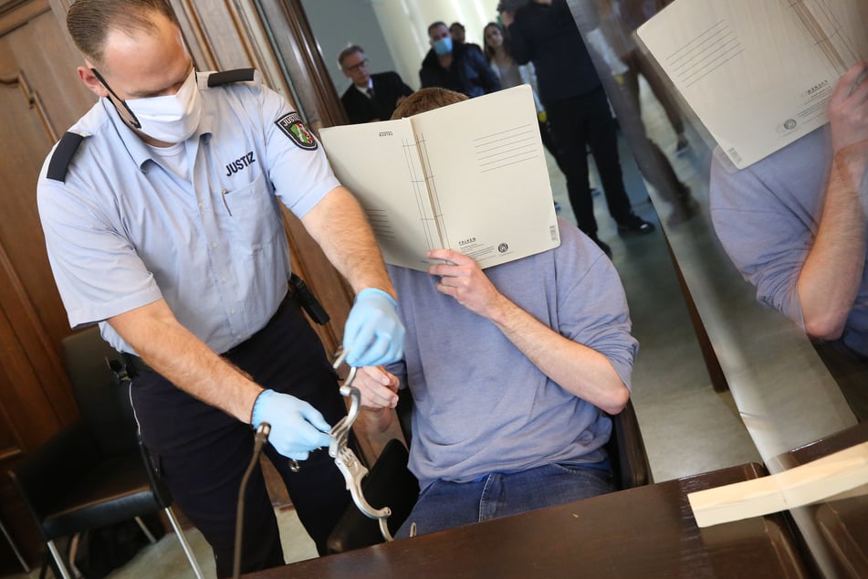 Dem Angeklagten Bastian S. (r) werden von einem Justizbeamten im Gerichtssaal die Handschellen abgenommen.