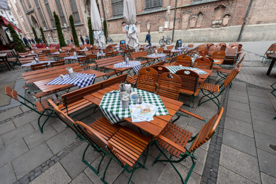 Leere gedeckte Tische stehen um die Mittagszeit vor einem Restaurant nahe der Frauenkirche (im Hintergrund) vor einem Restaurant.
