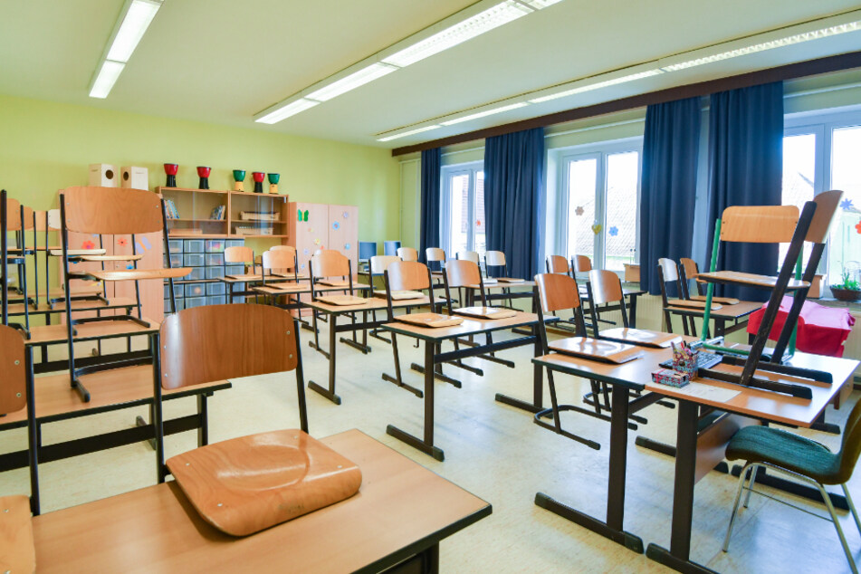 In einem leeren Unterrichtsraum an einer Grundschule sind die Stühle auf einen Tisch gestellt.