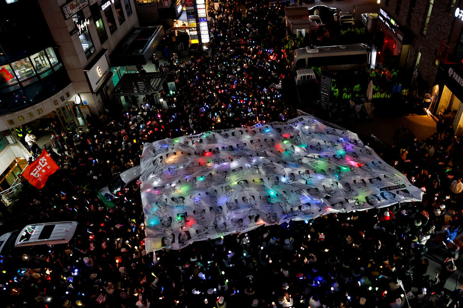 Protesters hold a banner depicting faces of ruling People Power Party lawmakers during a rally calling for the impeachment of South Korean President Yoon Suk Yeol in Seoul on December 12, 2024.