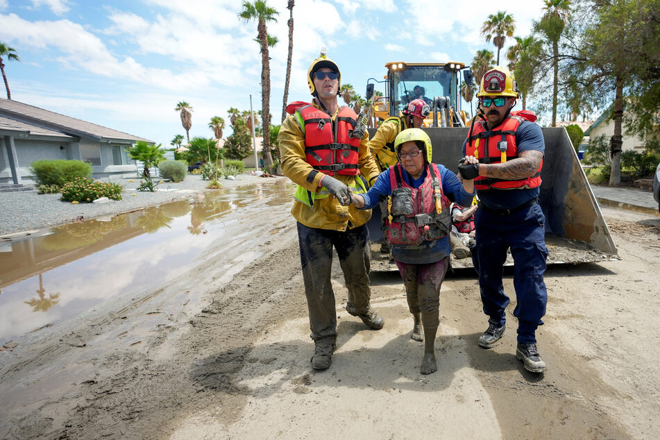 Firefighters and emergency medical personnel move a resident, who was trapped in a care home overnight, to an ambulance following Tropical Storm Hilary in Cathedral City, California.