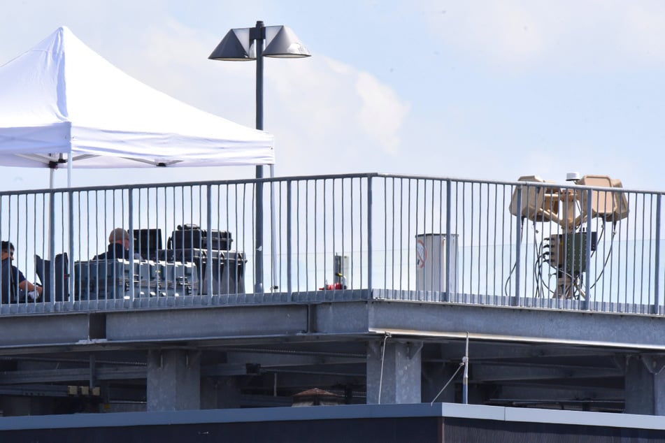 Polizeibeamte der Drohnenabwehr sitzen unter einem Sonnenschutz vor Monitoren, rechts daneben steht das EchoShield-Radar.