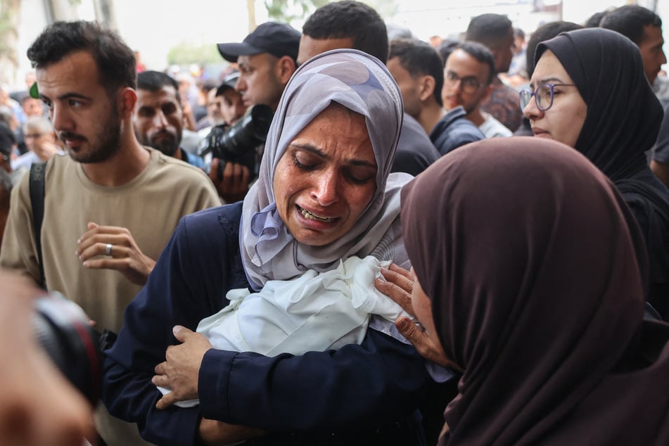A Palestinian woman cries as she carries the body of a baby killed in Israeli strikes on Gaza City, before a funeral procession outside the Al-Shifa hospital on September 4, 2025.