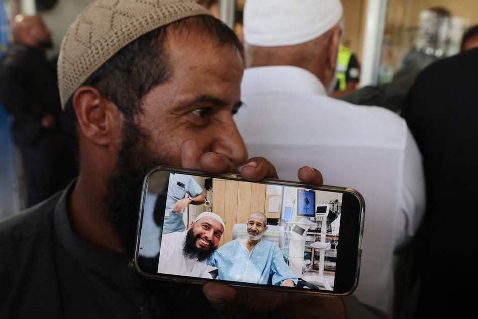 The brother of freed Israeli hostage Kaid Alkadi shows a cell phone picture of him with another brother after his arrival for a checkup at the Soroka Medical Center in Beersheva in southern Israel on Tuesday.