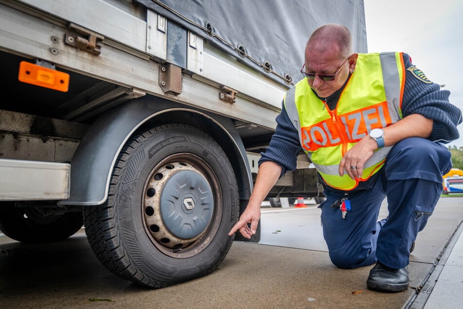 Polizeihauptmeister Frank Geisler zeigt die beanspruchten Reifen des überladenden Transporters aus Polen.